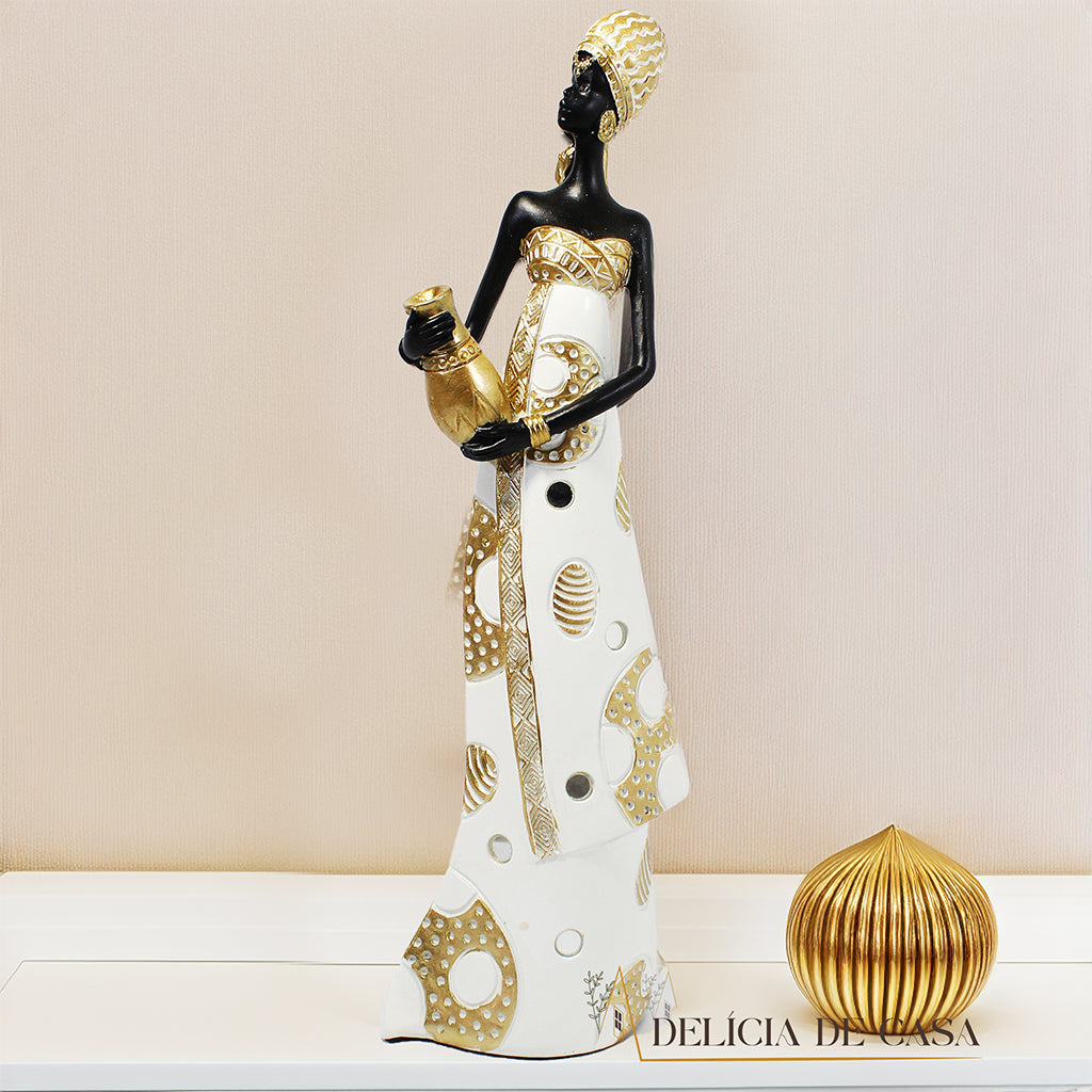 Estátua decorativa de mulher africana em resina nas cores branco, dourado e preto, com trajes típicos, medindo 32,5 cm de altura — peça elegante e cultural para decoração de interiores.