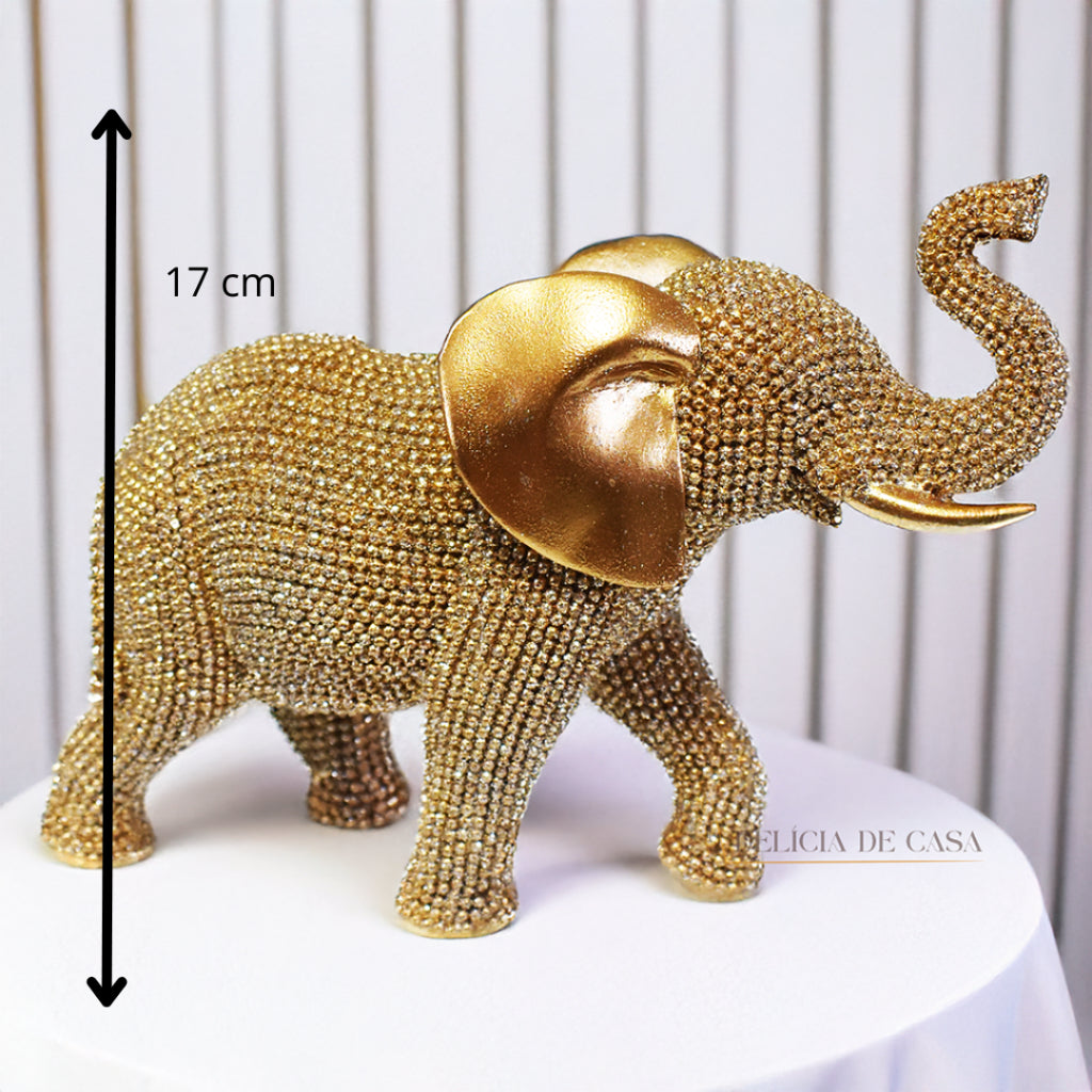 Escultura de elefante dourado coberto de strass, com tromba erguida e detalhes refinados, ideal para decoração luxuosa.