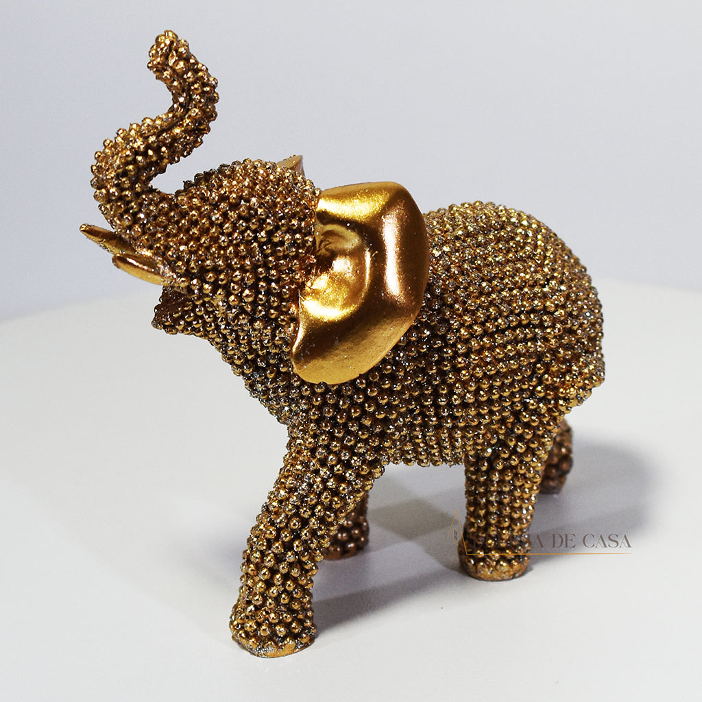Escultura de elefante dourado coberto de strass, com tromba erguida e detalhes refinados, ideal para decoração luxuosa.