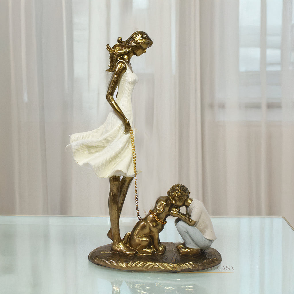 Estatueta decorativa de resina representando uma mãe segurando a coleira de um cachorro, enquanto seu filho se ajoelha e interage com o pet, simbolizando amor e conexão familiar.