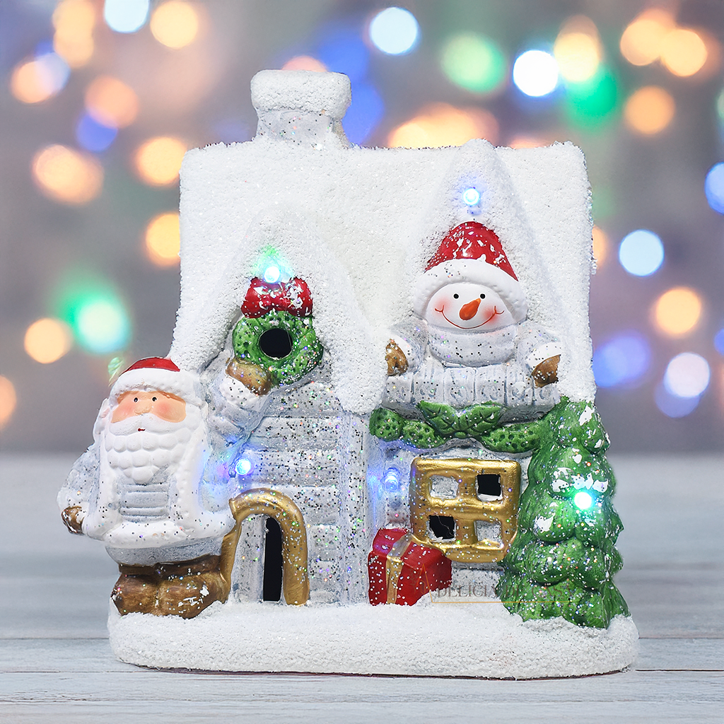 Casinha decorativa de Natal com Papai Noel, boneco de neve e árvore, feita em resina com glitter e luzes coloridas, 22 cm de altura.