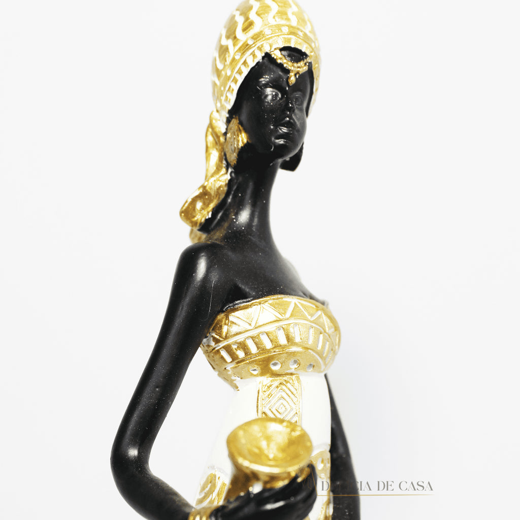 Estátua decorativa de mulher africana em resina nas cores branco, dourado e preto, com trajes típicos, medindo 32,5 cm de altura — peça elegante e cultural para decoração de interiores.