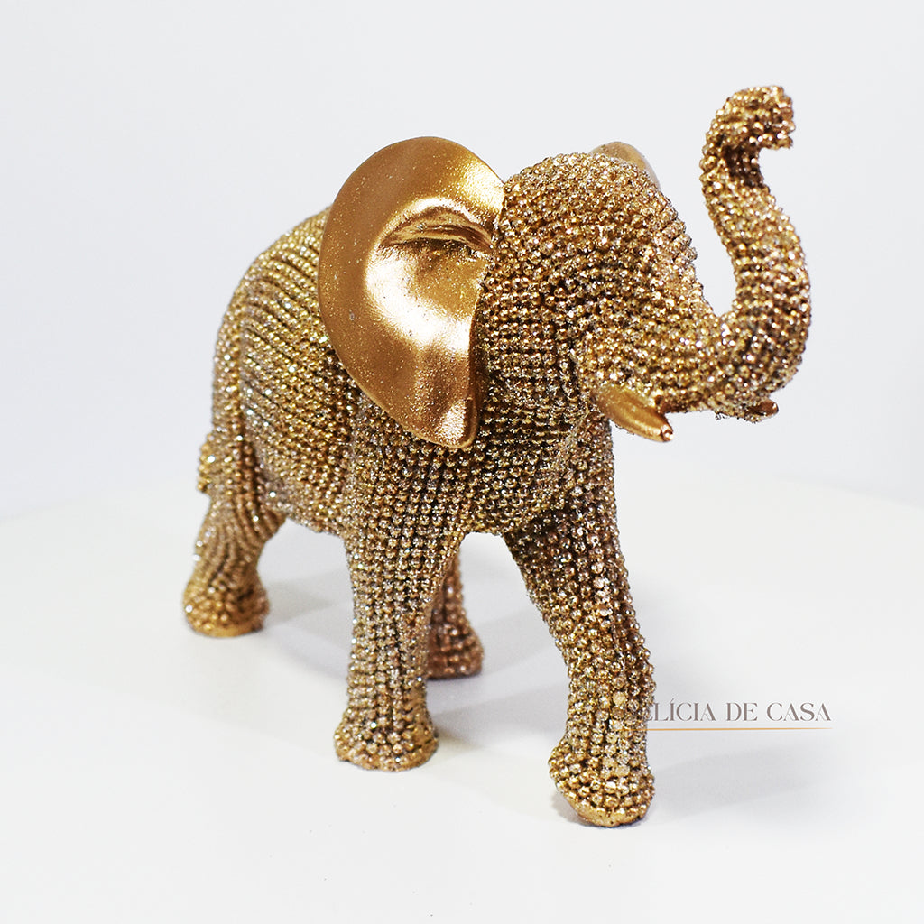 Escultura de elefante dourado coberto de strass, com tromba erguida e detalhes refinados, ideal para decoração luxuosa.
