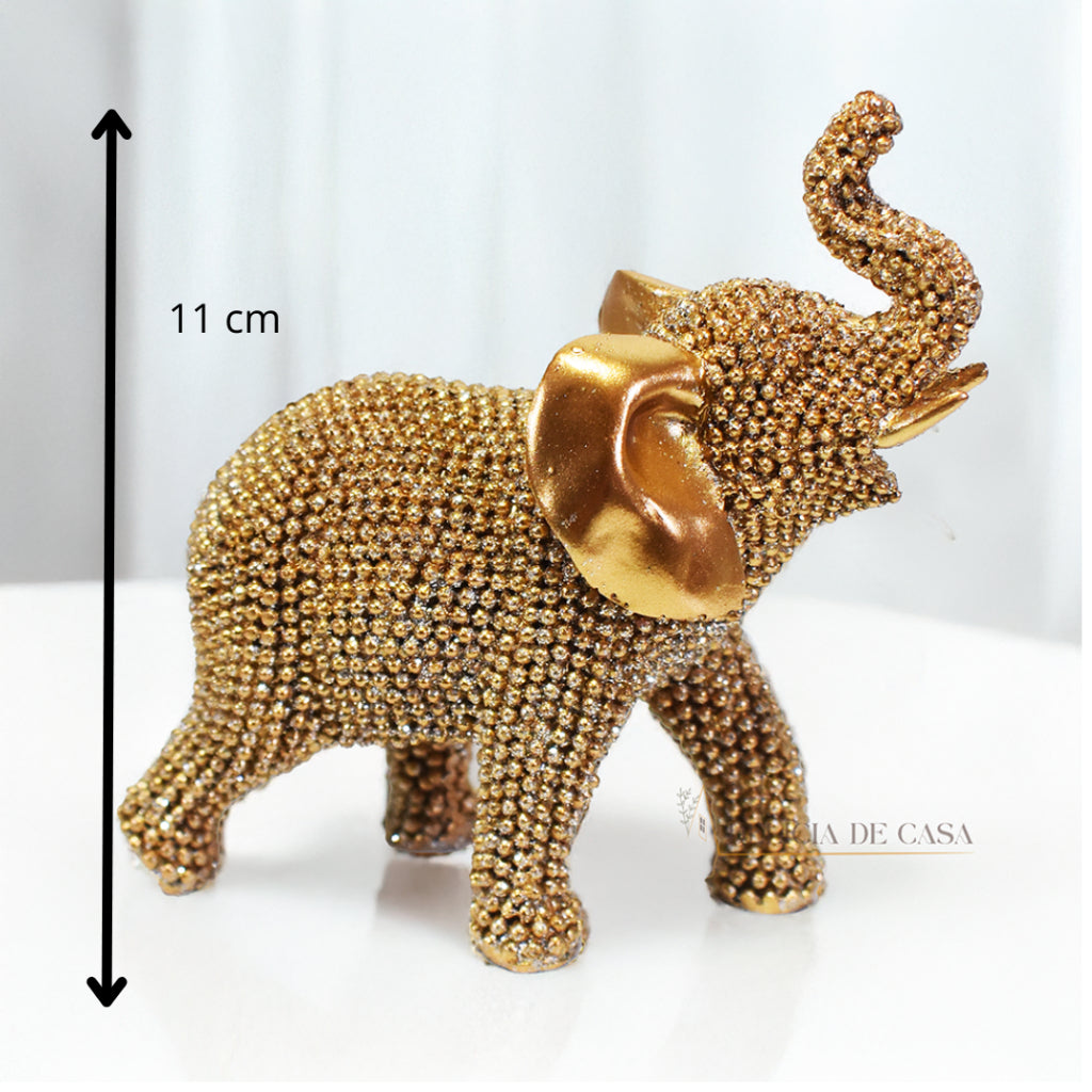 Escultura de elefante dourado coberto de strass, com tromba erguida e detalhes refinados, ideal para decoração luxuosa.