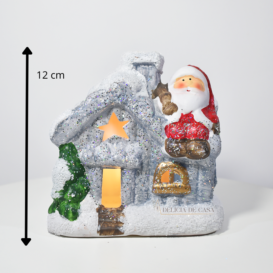 Casinha decorativa de Natal com Papai Noel e neve, feita em resina com glitter e luz interna, 12 cm de altura, nas cores bege, vermelho e cinza.