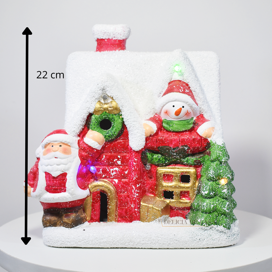 Casinha decorativa de Natal com Papai Noel, boneco de neve e árvore, feita em resina com glitter e luzes coloridas, 22 cm de altura.