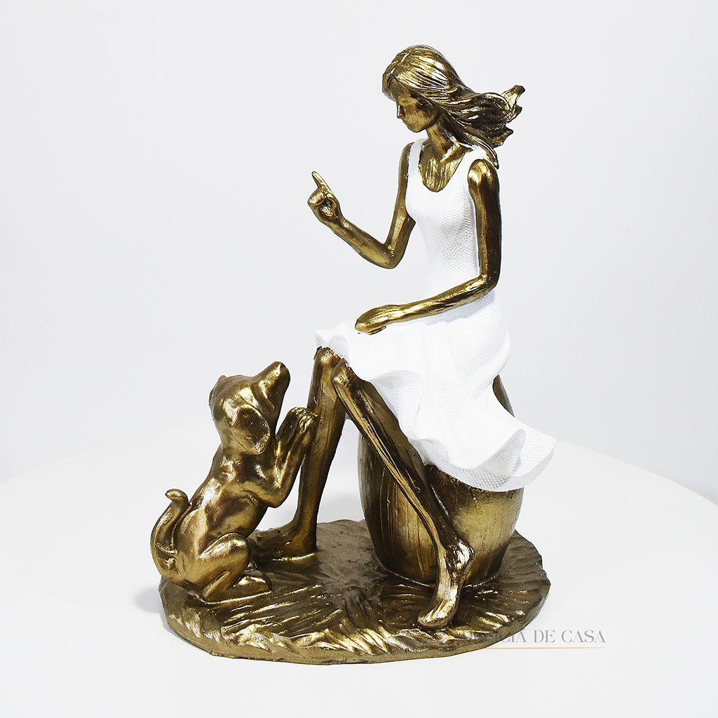 Escultura decorativa em resina de mulher sentada com cachorro em acabamento dourado para decoração de sala ou estante.