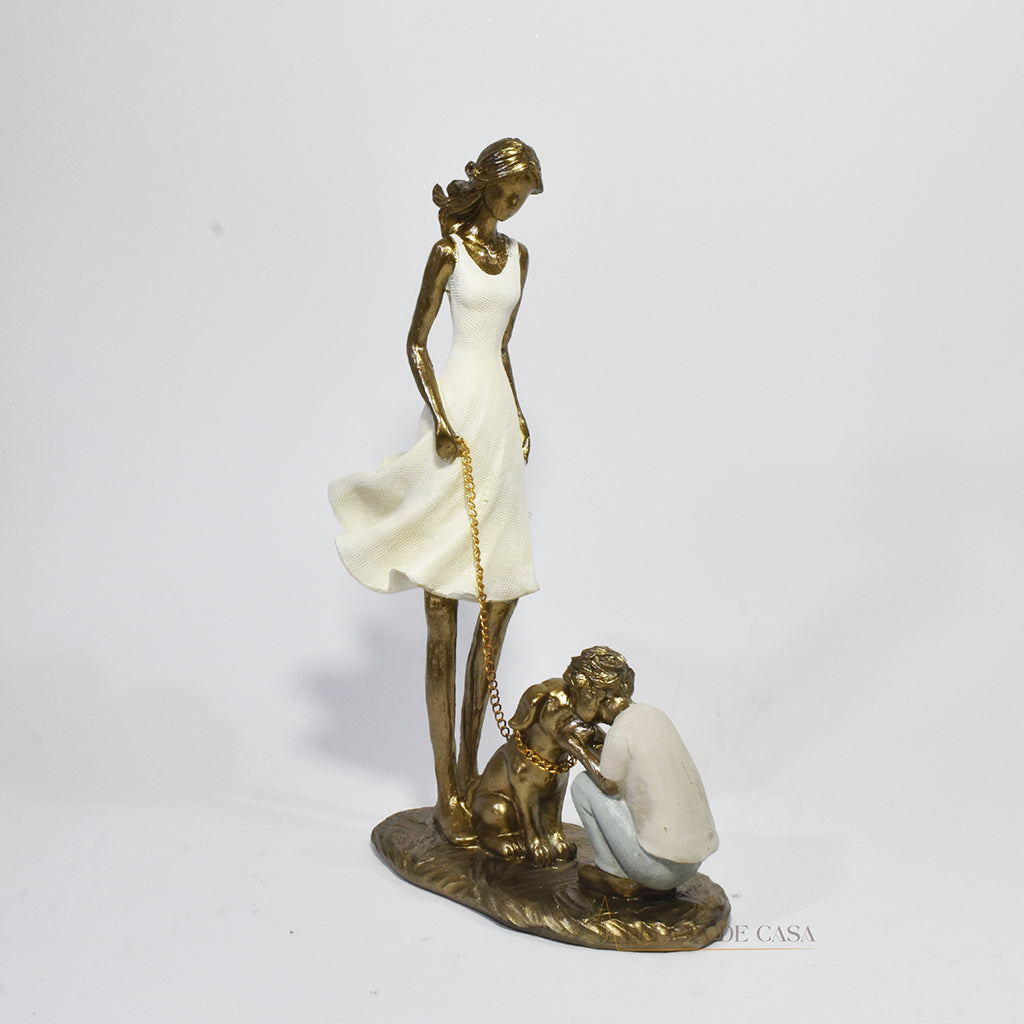 Estatueta decorativa de resina representando uma mãe segurando a coleira de um cachorro, enquanto seu filho se ajoelha e interage com o pet, simbolizando amor e conexão familiar.