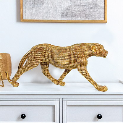 Escultura decorativa de leopardo dourado em resina com textura brilhante, apoiado em posição elegante sobre móvel.
