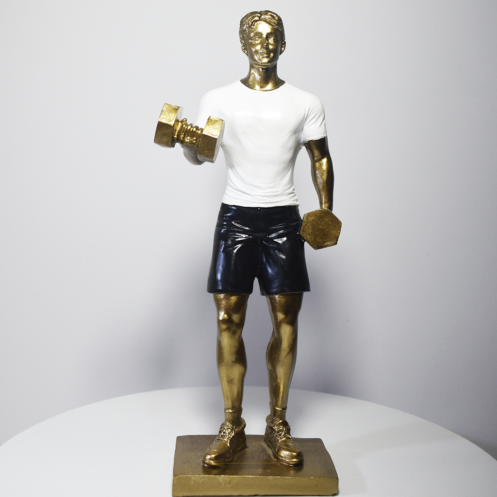 Escultura decorativa em resina representando atleta realizando exercício com halteres, com acabamento dourado, camiseta branca e shorts pretos.