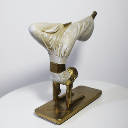 Escultura decorativa em resina de mulher praticando yoga em posição de equilíbrio, com acabamento dourado e branco perolado.