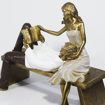 Escultura decorativa de casal romântico em resina sentados em um banco, com acabamento dourado, branco e marrom, simbolizando amor, cumplicidade e momentos especiais. 22,5x13x18 cm.