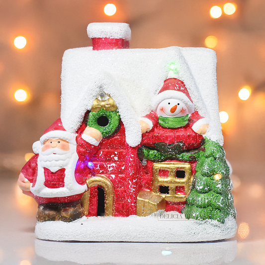 Casinha decorativa de Natal com Papai Noel, boneco de neve e árvore, feita em resina com glitter e luzes coloridas, 22 cm de altura.