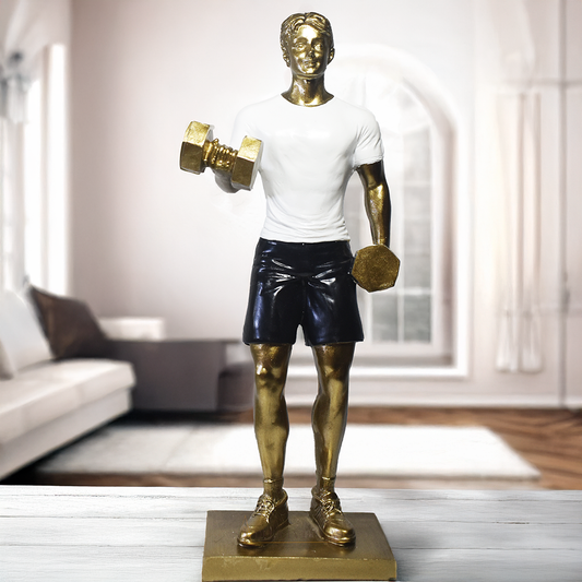 Escultura decorativa em resina representando atleta realizando exercício com halteres, com acabamento dourado, camiseta branca e shorts pretos.