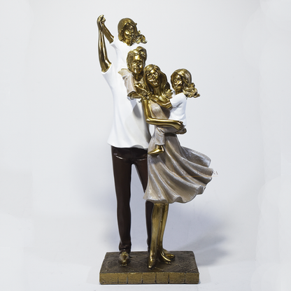 Escultura decorativa em resina representando pai, mãe e duas filhas em uma composição elegante e harmoniosa, com acabamento dourado, branco e marrom, simbolizando amor, união e felicidade familiar. Medidas 29,5x14x8,5 cm.