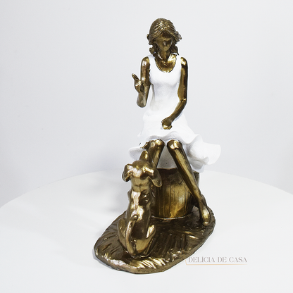 Escultura decorativa em resina de mulher sentada com cachorro em acabamento dourado para decoração de sala ou estante.