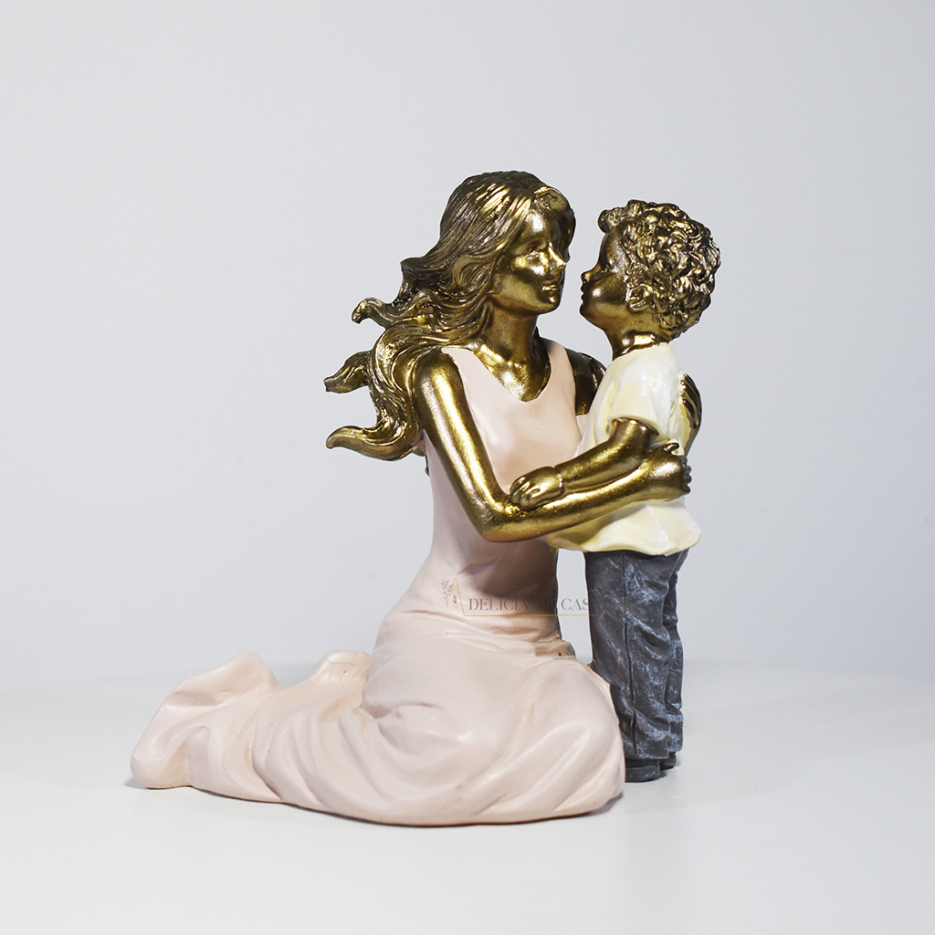 Escultura decorativa de mãe abraçando seu filho, confeccionada em resina com acabamento dourado, branco e cinza, medindo 11,5 x 11,5 x 8 cm.