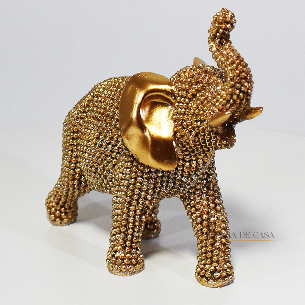 Escultura de elefante dourado coberto de strass, com tromba erguida e detalhes refinados, ideal para decoração luxuosa.