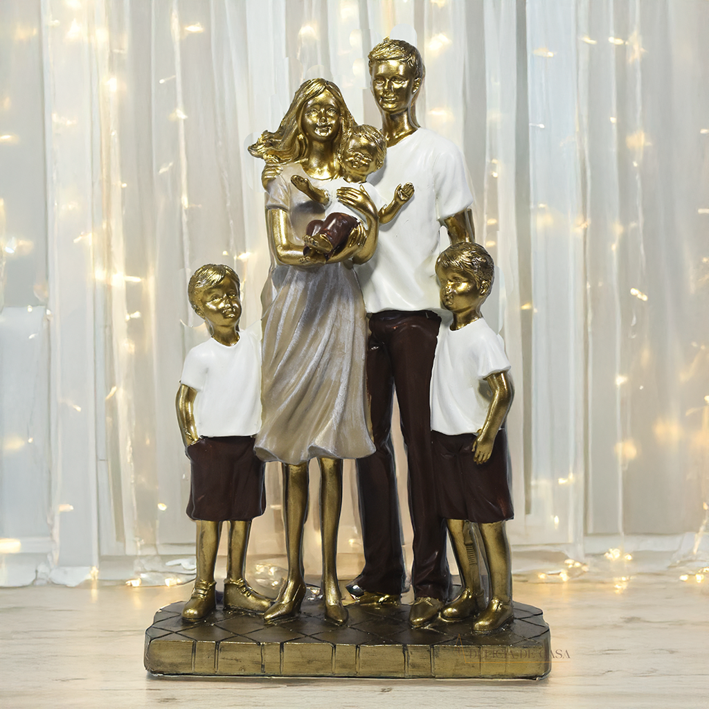 Escultura decorativa em resina representando família com pai, mãe e três filhos, acabamento dourado, branco e marrom, símbolo de amor, união e proteção familiar. Medidas de 25,5x17x8 cm.