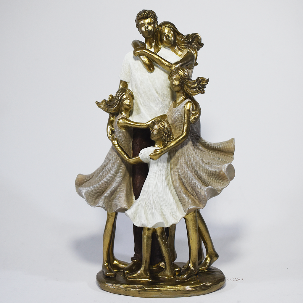 Escultura decorativa de família com pai, mãe e três filhas em abraço coletivo, confeccionada em resina com acabamento dourado e branco, medindo 25 x 15 x 8,5 cm.