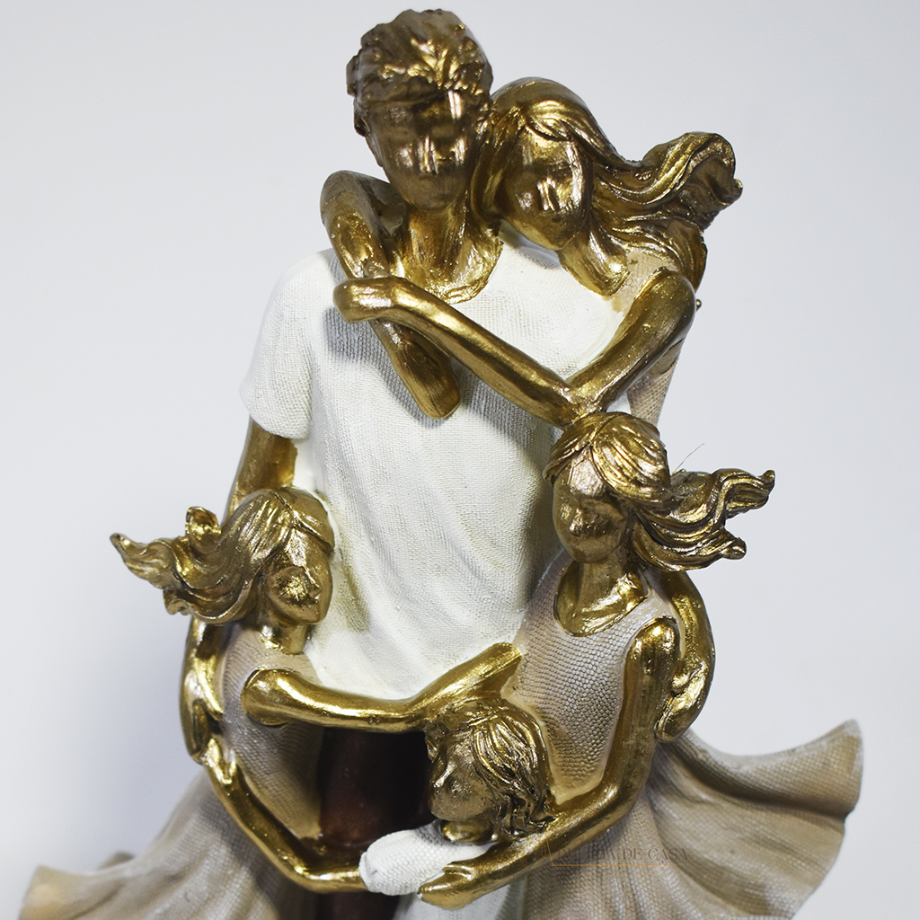 Escultura decorativa de família com pai, mãe e três filhas em abraço coletivo, confeccionada em resina com acabamento dourado e branco, medindo 25 x 15 x 8,5 cm.