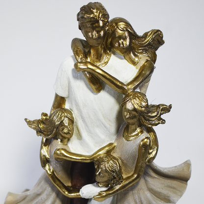 Escultura decorativa de família com pai, mãe e três filhas em abraço coletivo, confeccionada em resina com acabamento dourado e branco, medindo 25 x 15 x 8,5 cm.