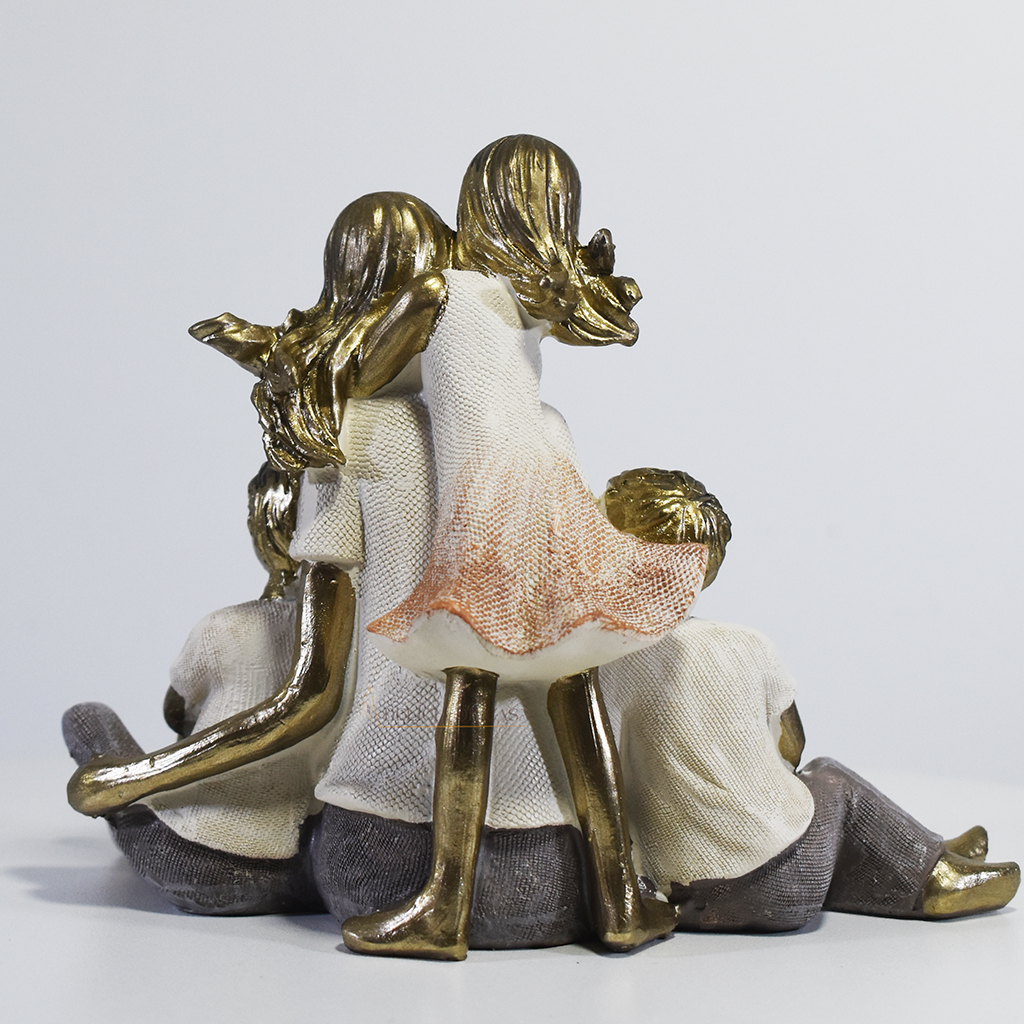 Escultura decorativa de mãe sentada com dois filhos e uma filha, confeccionada em resina com acabamento dourado, branco e cinza, medindo 15 x 11,5 x 8 cm.