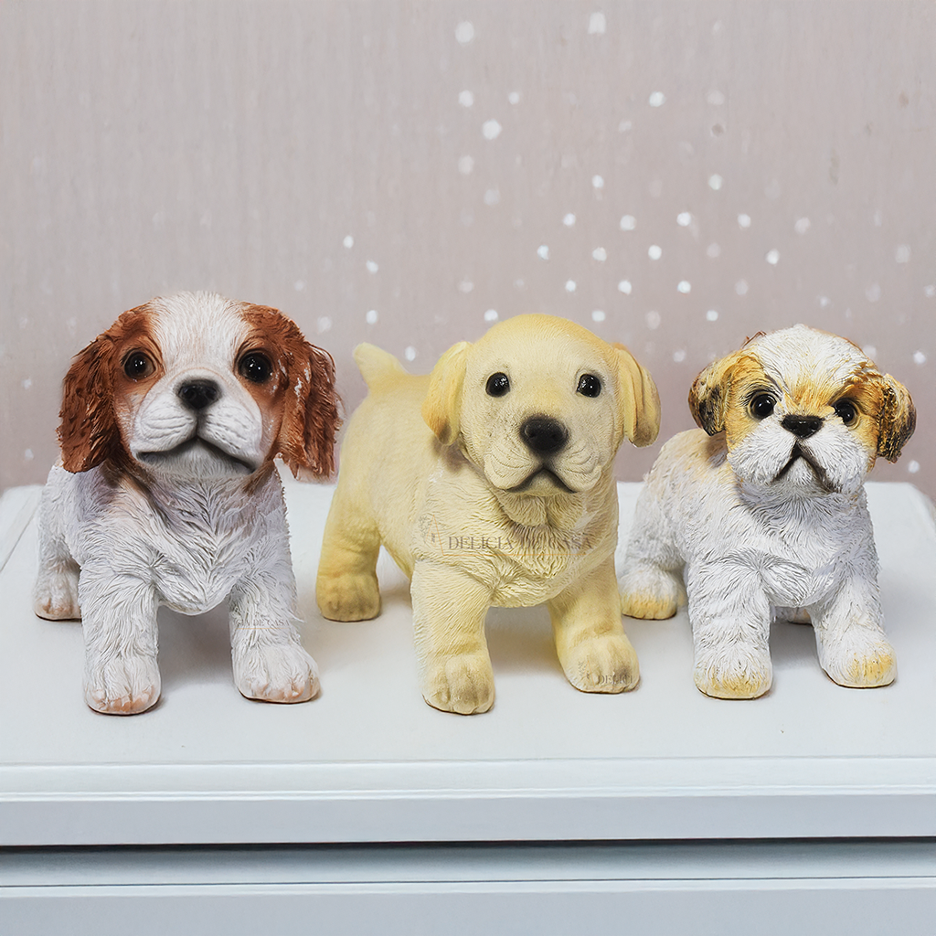 Esculturas decorativas de cachorros em resina representando as raças Labrador, Shih Tzu e Cavalier King Charles Spaniel, ideais para decoração ou presente.