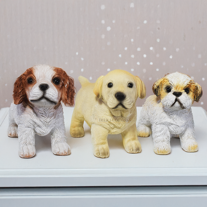 Esculturas decorativas de cachorros em resina representando as raças Labrador, Shih Tzu e Cavalier King Charles Spaniel, ideais para decoração ou presente.