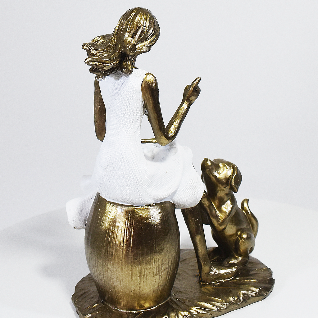 Escultura decorativa em resina de mulher sentada com cachorro em acabamento dourado para decoração de sala ou estante.