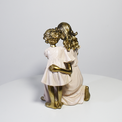 Escultura decorativa em resina representando mãe ajoelhada com dois filhos, simbolizando amor, cuidado, proteção e união familiar.