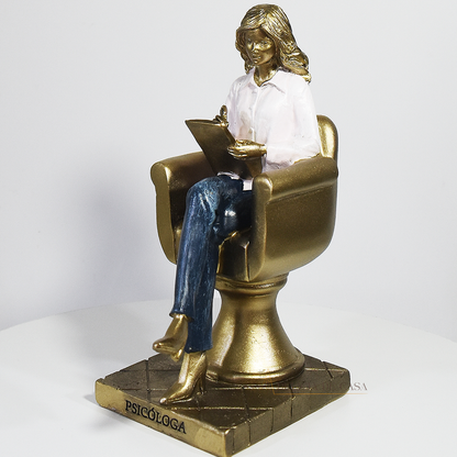 Escultura decorativa de psicóloga sentada em poltrona com prancheta, peça em resina ideal para decoração de consultório ou presente para psicóloga.