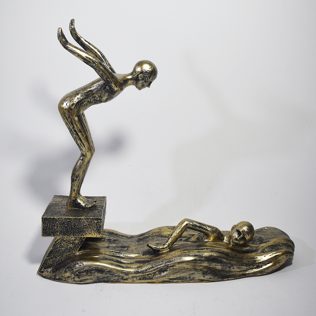 Escultura decorativa em resina representando atletas da natação, com um mergulhador e um nadador sobre ondas estilizadas em acabamento dourado envelhecido.