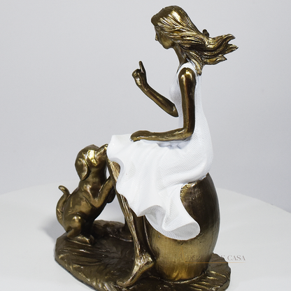 Escultura decorativa em resina de mulher sentada com cachorro em acabamento dourado para decoração de sala ou estante.