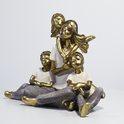 Escultura decorativa de mãe sentada com dois filhos e uma filha, confeccionada em resina com acabamento dourado, branco e cinza, medindo 15 x 11,5 x 8 cm.