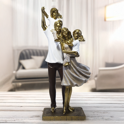 Escultura decorativa em resina representando pai, mãe e duas filhas em uma composição elegante e harmoniosa, com acabamento dourado, branco e marrom, simbolizando amor, união e felicidade familiar. Medidas 29,5x14x8,5 cm.