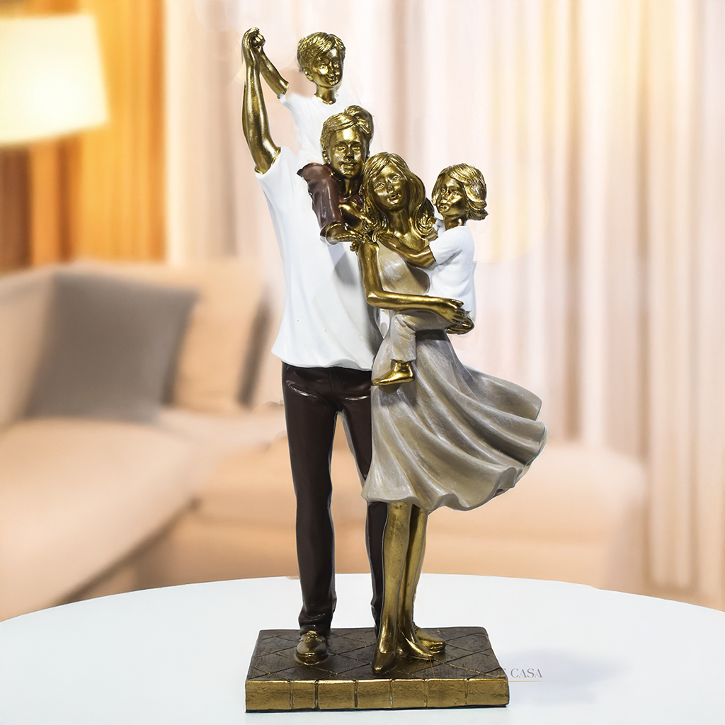 Escultura decorativa de família com pai, mãe, um filho e uma filha, confeccionada em resina com acabamento dourado, branco e marrom, medindo 29,5 x 14 x 8,5 cm.