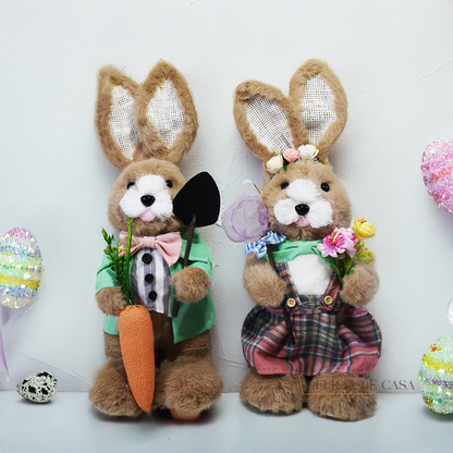 Coelho de pelúcia decorativo vestido com roupa social verde, segurando uma cenoura e uma enxada, ideal para decoração de Páscoa e ambientes rústicos.