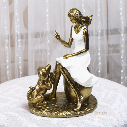 Escultura decorativa em resina de mulher sentada com cachorro em acabamento dourado para decoração de sala ou estante.