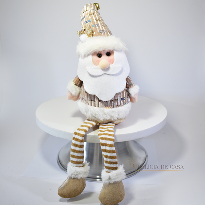 Boneco decorativo de Papai Noel sentado com pernas longas, roupas douradas e barba branca, ideal para decoração natalina em mesas e prateleiras.