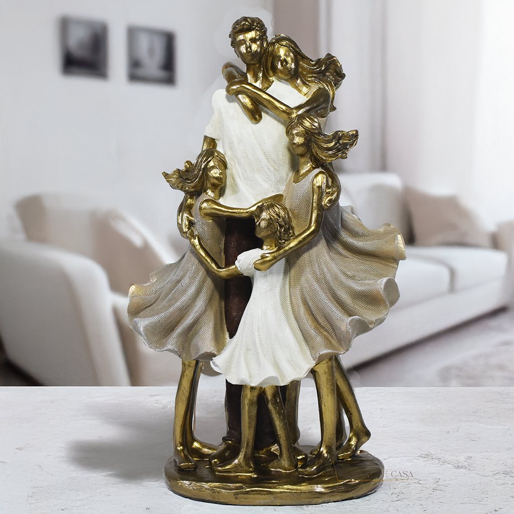 Escultura decorativa de família com pai, mãe e três filhas em abraço coletivo, confeccionada em resina com acabamento dourado e branco, medindo 25 x 15 x 8,5 cm.
