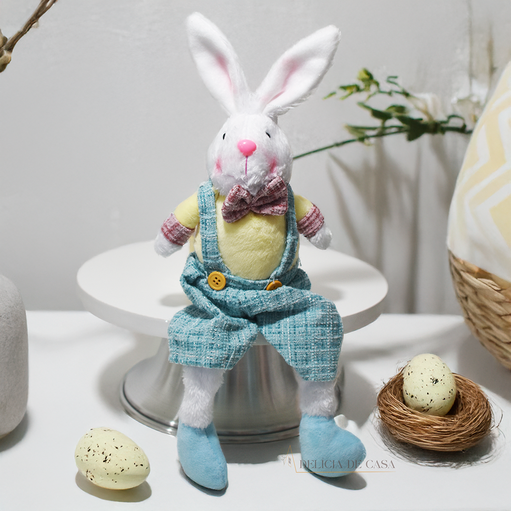 Coelho decorativo de Páscoa em pelúcia sentado, com roupa em tons suaves, perfeito para decoração de casa e ambientes temáticos.
