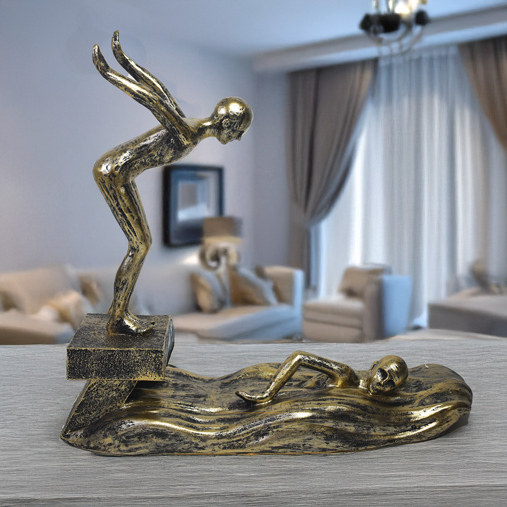 Escultura decorativa em resina representando atletas da natação, com um mergulhador e um nadador sobre ondas estilizadas em acabamento dourado envelhecido.