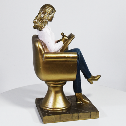 Escultura decorativa de psicóloga sentada em poltrona com prancheta, peça em resina ideal para decoração de consultório ou presente para psicóloga.
