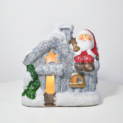 Casinha decorativa de Natal com Papai Noel e neve, feita em resina com glitter e luz interna, 12 cm de altura, nas cores bege, vermelho e cinza.