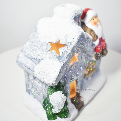 Casinha decorativa de Natal com Papai Noel e neve, feita em resina com glitter e luz interna, 12 cm de altura, nas cores bege, vermelho e cinza.