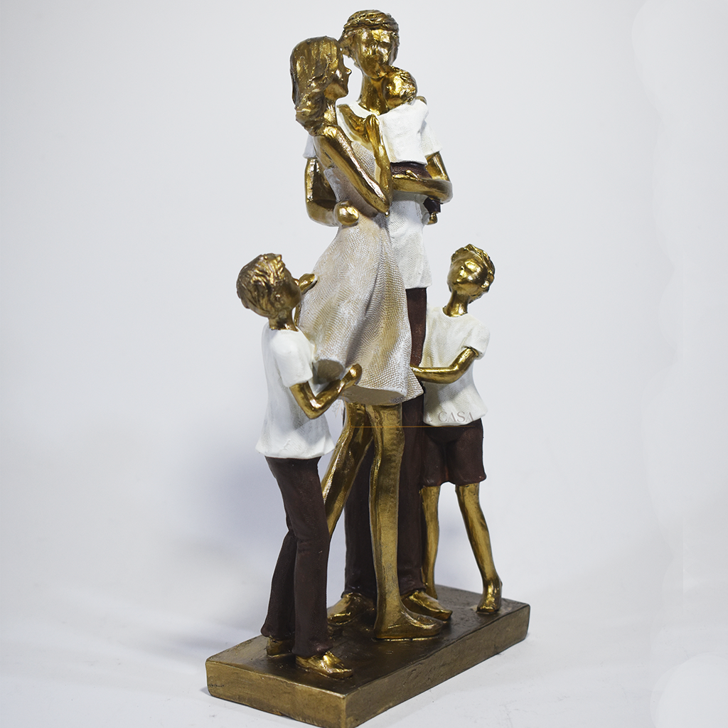 Escultura decorativa em resina representando casal com três filhos em um momento de união familiar, com acabamento dourado, branco e marrom, medindo 25,5 x 17 x 8 cm.