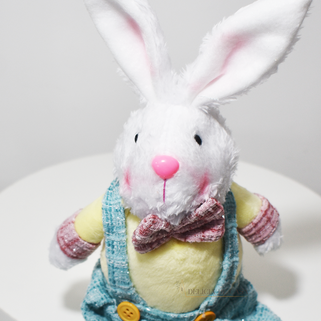 Coelho decorativo de Páscoa em pelúcia sentado, com roupa em tons suaves, perfeito para decoração de casa e ambientes temáticos.