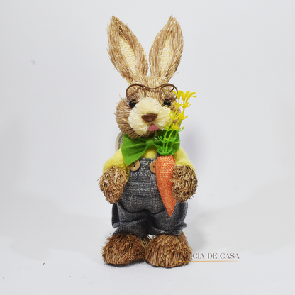 Coelho de palha decorativo disponível nas versões masculina (com macacão e cenoura) e feminina (com vestido laranja e cesta), perfeitos para decoração de Páscoa.