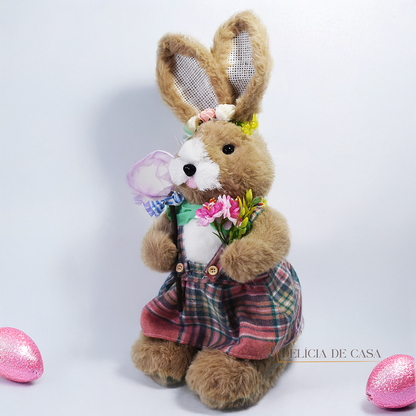 Coelho de pelúcia decorativo vestido com roupa social verde, segurando uma cenoura e uma enxada, ideal para decoração de Páscoa e ambientes rústicos.